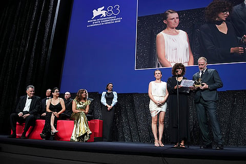 Jury members Francesco Casetti, from left, Johnnie To, Shahrbanoo Sadat, Daniel Blumberg and Kaouther Ben Hania and jury president Maggie Gyllenhaal look on as Mathilde Arcel, director May el-Toukhy and producer Mikael Christian Rieks accept the Golden Lion for best film for 'Woman Unknown' during the closing ceremony of the 83rd edition of the Venice Film Festival in Venice, Italy.