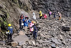 SDRF personnel evacuate stranded pilgrims after debris and stones temporarily closed the Kedarnath Yatra trekking route near Chirbasa helipad, in Rudraprayag, Uttarakhand. - | Photo: PTI