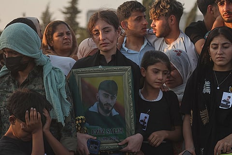 A mourner holds a portrait of one of the prisoners who died in a fire that broke out during unrest at the local prison, during a mass funeral in the predominantly Kurdish city of Kobani, northern Syria.