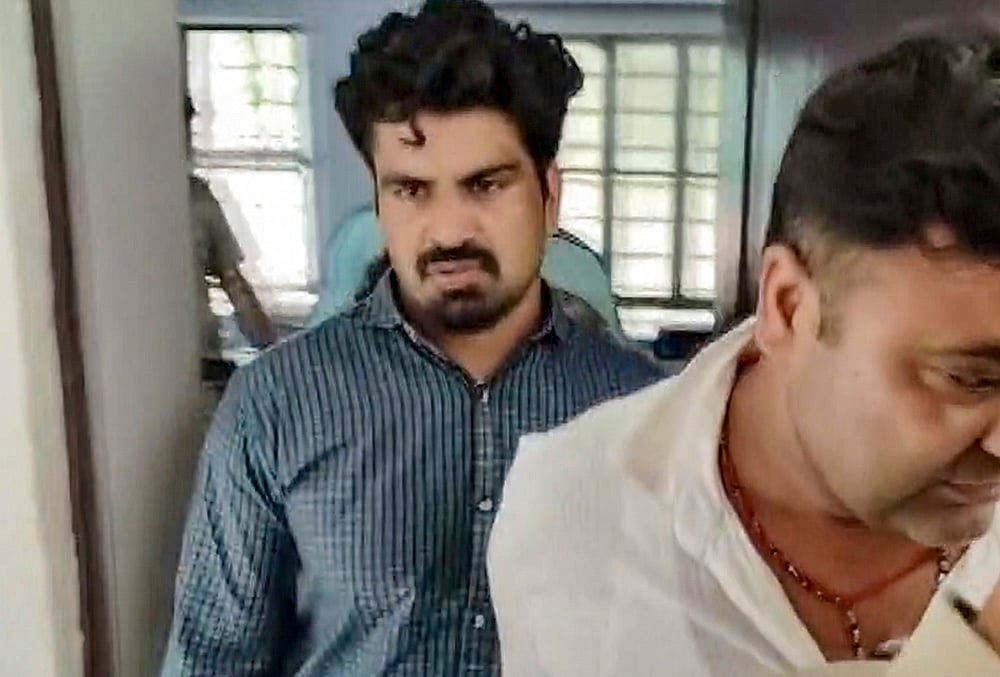 Police personnel escort Kalyan Bainsla, accused of chasing and ramming his car into woman biker Shivani Chauhan (Sia) on Gurugram's Golf Course Road, following his arrest in Dausa district, Rajasthan.
 - | Photo: PTI