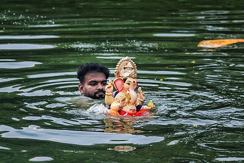 A man immerses an idol of Lord Ganesh on the second day of Ganesh Chaturthi festival, in Navi Mumbai.