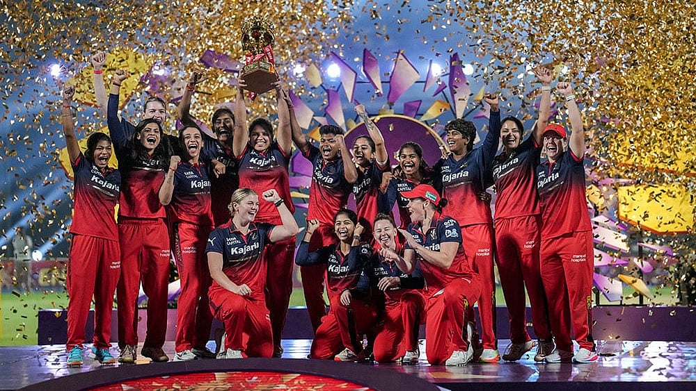 Royal Challengers Bengaluru's players celebrate with the trophy after winning the Women's Premier League (WPL) 2026 final T20 cricket match against Delhi Capitals, at Baroda Cricket Association Stadium, Kotambi in Vadodara, Gujarat - Photo: PTI/Kunal Patil
