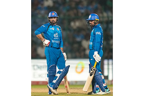 Afghanistan's Mohammed Nabi, left, and Rashid Khan interact between the wickets during the second T20I cricket match between India and Afghanistan, in New Delhi.