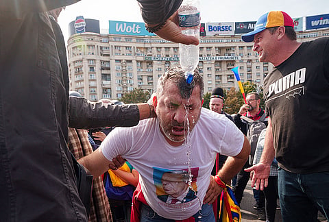 A man that was sprayed with tear gas is helped after a scuffle with riot police during a farmers' protest in Bucharest, Romania, Tuesday, Sept. 15, 2026. 