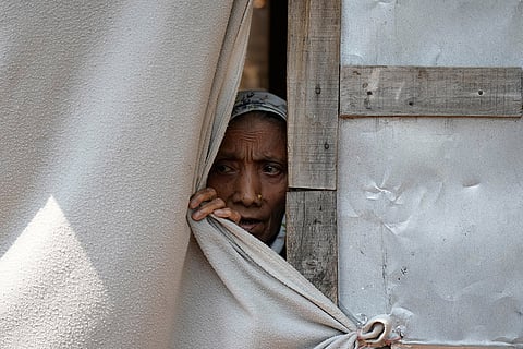 A Rohingya woman looks out from a blanket used as a wall at a temporary shelter where refugees live following government notices ordering the removal of unauthorized structures in Jammu, India.