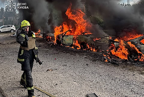 A firefighters walk past burning cars as they work at the site, following a Russian air attack in Kyiv, Ukraine, Wednesday, Sept. 16, 2026. 