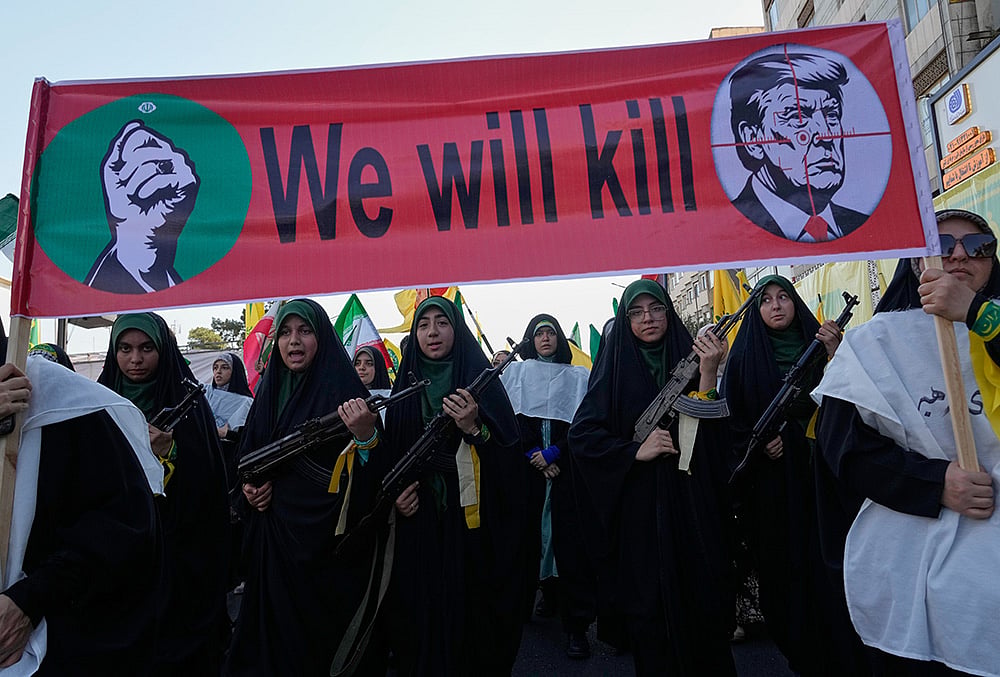 Women affiliated with Iran's Revolutionary Guard carry rifles as they march beneath a banner depicting U.S. President Donald Trump in crosshairs and reading "We will kill" during the state-organized "Janfada," or "Sacrifice for Iran," military-style parade in Tehran, Iran, Friday, Sept. 18, 2026.  - | Photo: AP/Vahid Salemi