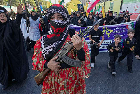 A woman with her face covered carries a rifle as she marches with other armed women and children carrying toy guns during the state-organized "Janfada," or "Sacrifice for Iran," military-style parade in Tehran, Iran, Friday, Sept. 18, 2026. 
