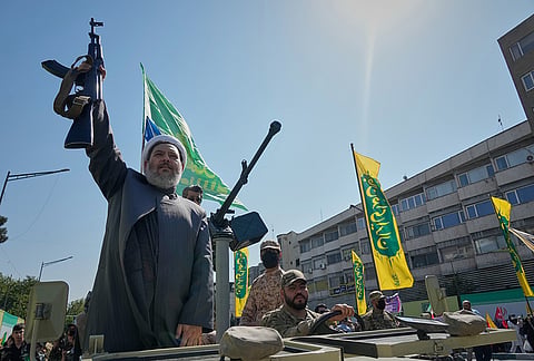 An armed Shiite cleric holds up a rifle as he rides aboard a military vehicle during the state-organized "Janfada," or "Sacrifice for Iran," military-style parade in Tehran, Iran, Friday, Sept. 18, 2026. 