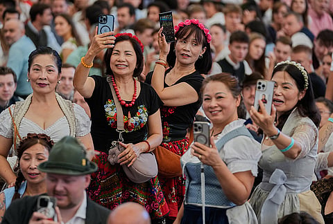 Visitors take pictures of the Oktoberfest parade at the 191st Oktoberfest beer festival in Munich, Germany, Saturday, Sept.19, 2026. 
