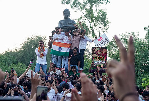 Independent candidate Deepanshu Shokeen, garlanded, celebrates with others atop Swami Vivekanand's statue after winning the vice-president's post in the Delhi University Students' Union (DUSU) elections, at North Campus, in New Delhi, Saturday, Sept. 19, 2026. 
