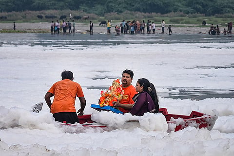 People immerse an idol of Lord Ganesha in the Yamuna River at Kalindi Kunj, in New Delhi, Delhi.