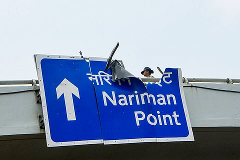A police official stands near a damaged overhead road sign after a BMW car crashed on the Coastal Road while moving at a high speed from Marine Drive towards Haji Ali, in Mumbai, Maharashtra. Three persons were killed and one was critically injured in the incident.