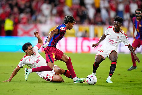 Barcelona's Lamine Yamal, centre, challenges for the ball with Sevilla's Gabriel Suazo, left, and Felix Correia during the Spanish La Liga soccer match between Sevilla and Barcelona in Seville, Spain.