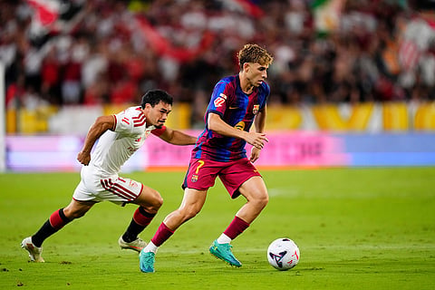 Barcelona's Fermin Lopez, right, and Sevilla's Gabriel Suazo challenge for the ball during the Spanish La Liga soccer match between Sevilla and Barcelona in Seville, Spain.