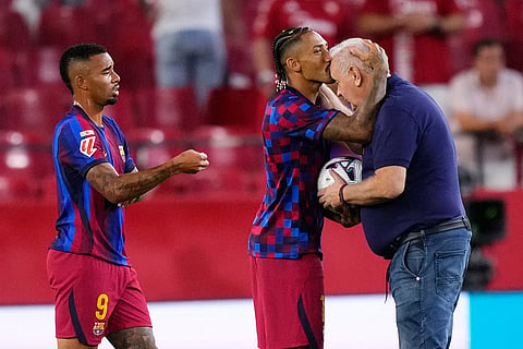 Barcelona's Raphinha, centre, hugs with first-team delegate Carles Naval, as Barcelona's Gabriel Jesus looks on after the Spanish La Liga soccer match between Sevilla and Barcelona in Seville, Spain.