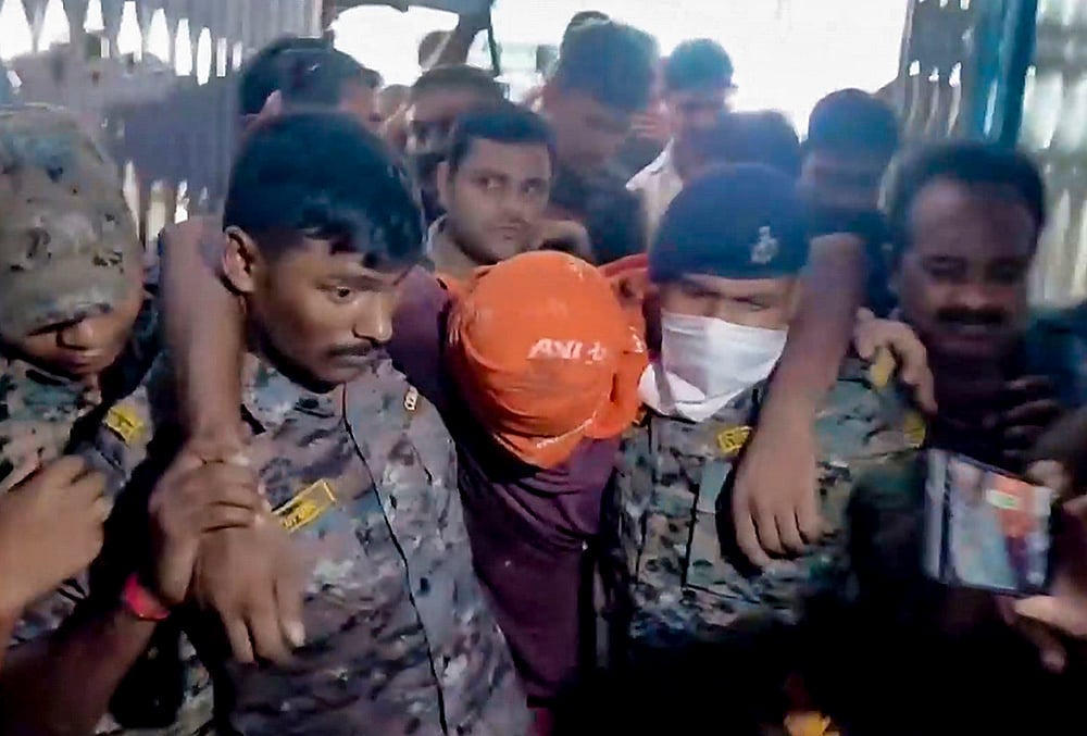 Security personnel carry an accused allegedly involved in the harassment of a boy and a girl by the roadside.  - | Photo: PTI 