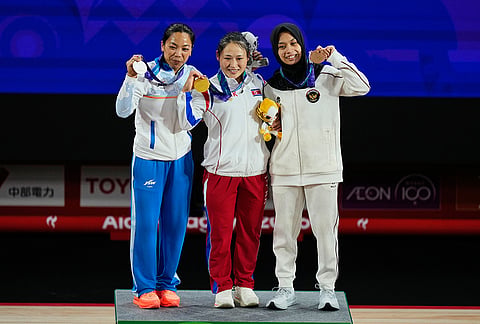 Gold Medalist Ri Song Gum of North Korea, center, Mirabai Chanu Saikhom of India, left, and Luluk Diana Tri Wijayana of Indonesia pose on the podium after the women's 49kg weightlifting final at the Asian Games in Nagoya, Japan, Wednesday, Sept. 23, 2026. 