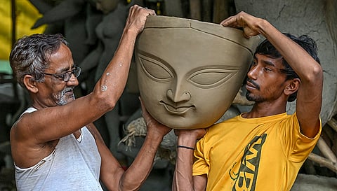 Artisans hold a clay face structure of Goddess Durga at a workshop ahead of the 'Durga Puja' festival, in Nadia district, West Bengal.