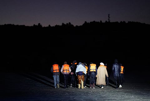 A group of migrants walk on a beach as they try to cross the channel from France to Britain on a dinghy boat, in Hardelot, northern France, Wednesday, Sept. 23, 2026. 
