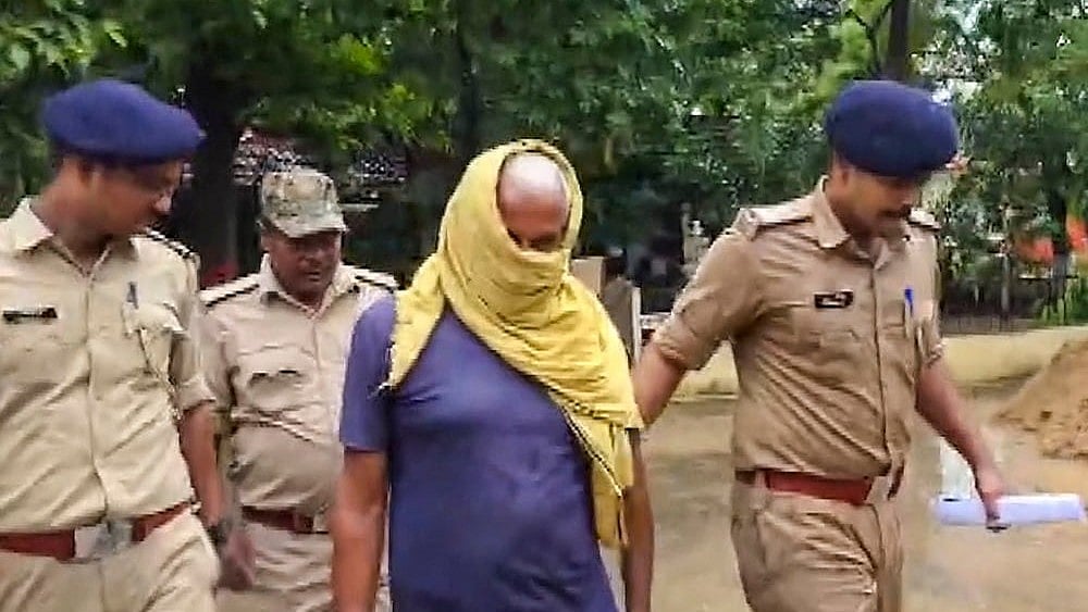 Police personnel escort the father of Nandan Yadav, the main accused in the Jamui minor girl harassment case, following his arrest in connection with a separate murder case, in Jamui, Bihar, Wednesday, Sept. 23, 2026.  - | Photo: PTI
