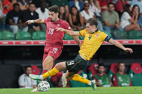 Portugal's Pedro Neto, left is tackled by Wales' Ben Davies during the Nations League soccer match between Portugal and Wales in Lisbon.