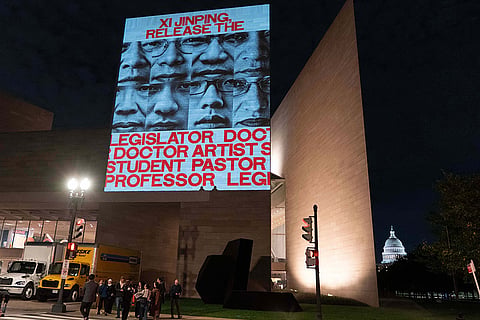 Demonstrators protest as they project faces of jailed activists during a protest against China's President Xi Jinping outside of the National Gallery of Art building Wednesday, Sept. 23, 2026, in Washington.