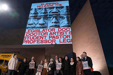 Demonstrators protest as they project faces of jailed activists during a protest against China's President Xi Jinping outside of the National Gallery of Art building Wednesday, Sept. 23, 2026, in Washington.