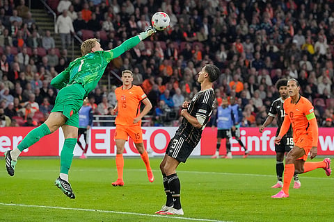 Netherlands goalkeeper Bart Verbruggen punches the ball in front of Germany's Younes Ebnoutalib during the UEFA Nations League soccer match between the Netherlands and Germany in Amsterdam, Netherlands.
