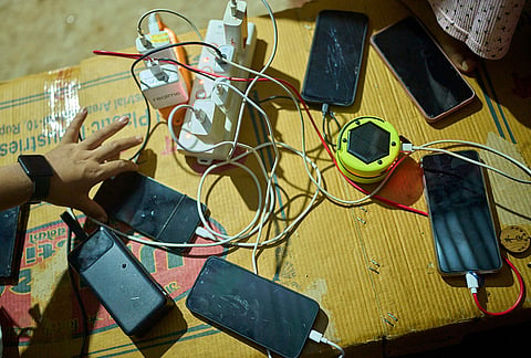 Survivors of a flash flood charge their cell phone at a temporary holding center in Nuwakot, Nepal, Sept. 22, 2026.  