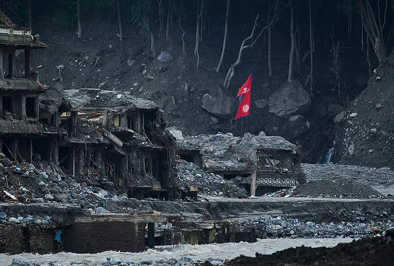 A Nepalese flag flies amid houses damaged by flash floods along the banks of the Trishuli River in Dunge, in Nepal's Nuwakot district, Wednesday, Sept. 23, 2026. - | Photo: AP/Niranjan Shrestha