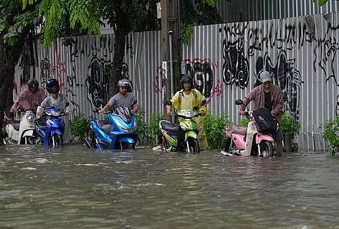 Men push motorcycles as they wade through floodwaters after heavy rain in Bangkok, Thailand Saturday, Sept. 26, 2026. 