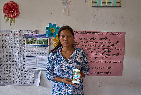 Pasang Maya Tamang stands inside a classroom converted into a temporary shelter as she shows a photograph of her 5-year-old son, who was swept away by flash floods, in Nepal's Nuwakot district, Tuesday, Sept. 8, 2026.