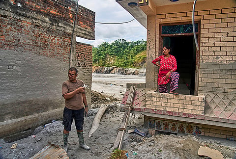 Narayan Prasad Nepal, left, stands outside his damaged house by a flash flood in Galchi, Nuwakot, Nepal, Wednesday, Sept. 23, 2026.
