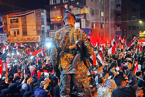 A Yemeni soldier stands alert as people wave national flags to celebrate the 64th anniversary of the September 26 Revolution in Taiz, Yemen, Friday, Sept. 25, 2026.