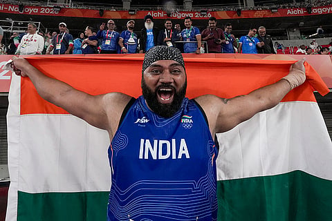 India's Tajinderpal Singh Toor holds a National Flag as he celebrates after winning a silver medal in the men's shot put final event during the 20th Asian Games, in Nagoya, Japan, Saturday, Sept. 26, 2026.
