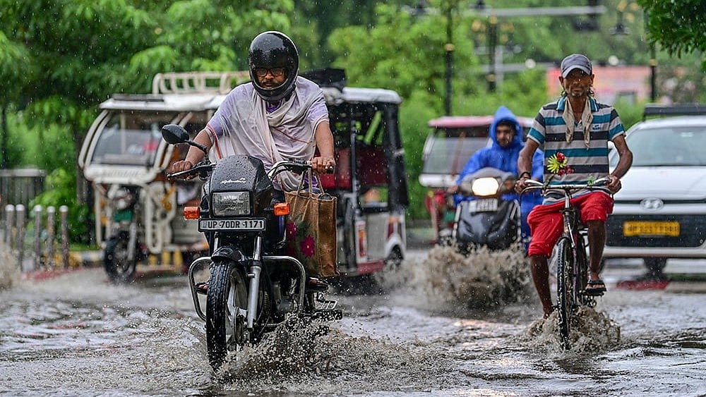 Commuters move through a waterlogged road during monsoon rain, in Prayagraj, Uttar Pradesh. - | Photo; PTI