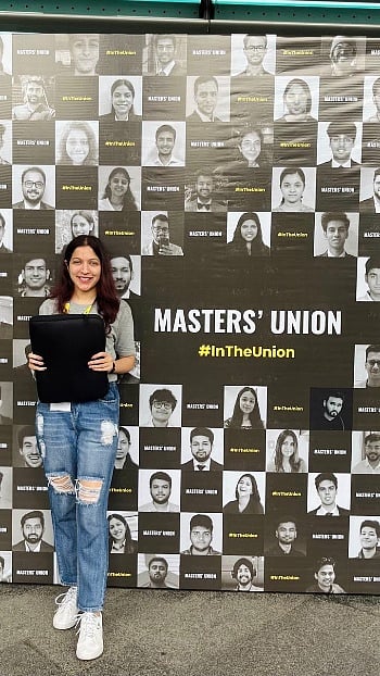 Ishita Gupta holding a laptop sleeve in front of a Masters Union backdrop
