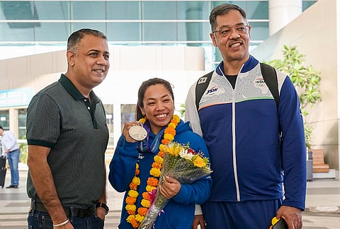 Indian weightlifter Saikhom Mirabai Chanu, centre, poses with her silver medal won at the 20th Asian Games upon her arrival at Indira Gandhi International Airport, in New Delhi.