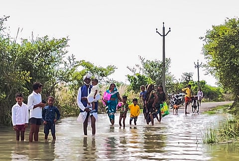 Villagers wade through a waterlogged road following a rise in the water level of the Ghaghra river, in Gonda district, Uttar Pradesh.