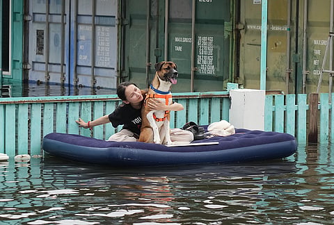 A woman with her dog rides a rubber raft through a flooded street after heavy rain in Bangkok, Thailand, Monday, Sept. 28, 2026. 