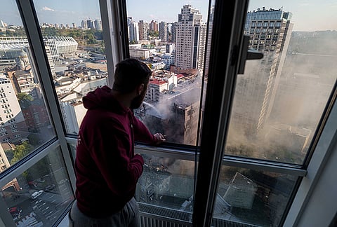 A man looks from his appartment at the burning Dobrobut Hospital after a Russian drone strike in central Kyiv, Ukraine, Monday, Sept. 28, 2026. 