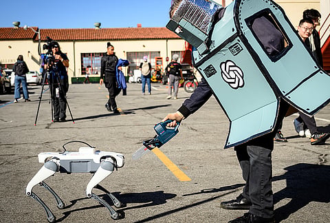 An AI protester pretends to cut a robot dog with a fake chain saw during a protest outside the OpenAI DevDay 2026 conference in San Francisco, on Tuesday, Sept. 29, 2026. 

