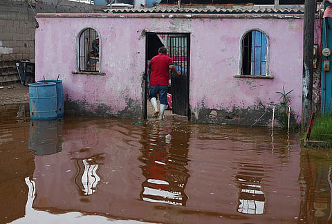 A resident enters his home surrounded by water brought by Hurricane Polo in Puerto San Carlos, Baja California Sur state, Mexico, Tuesday, Sept. 29, 2026. 
