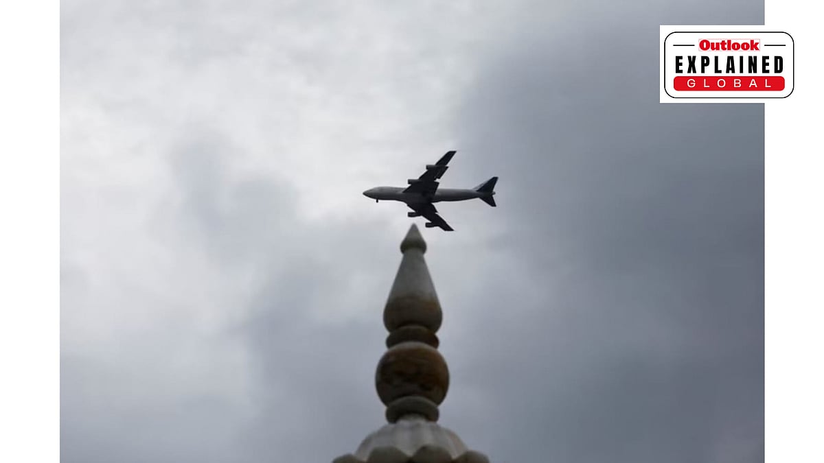 A plane flies past a monumemt with the rain clouds in the background, during the monsoon season in Karachi - Reuters