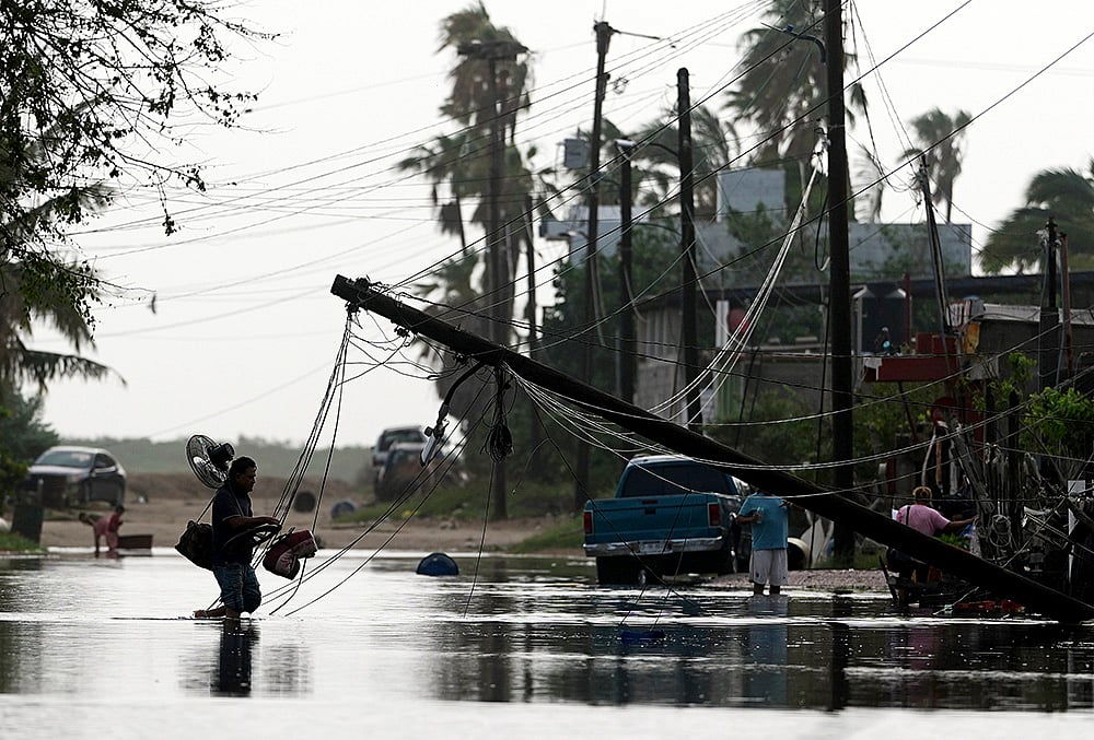 A man carries items through floodwater past downed electric lines after the passing of Hurricane Polo in Puerto San Carlos, Baja California Sur state, Mexico, Tuesday, Sept. 29, 2026. 
 - | Photo: AP/Eduardo Verdugo
