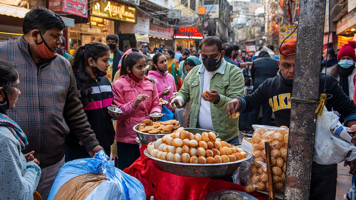 A street vendor with his customers at a food stall in Chandni Chowk in Old Delhi - Pradeep Gaurs/Shutterstock