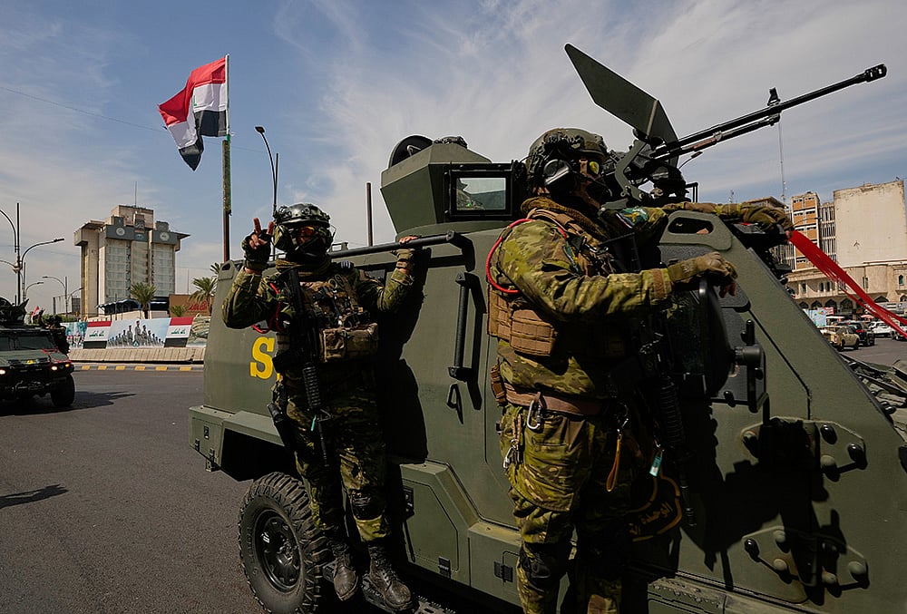 Iraqi police officers stand beside security vehicles decorated with national flags and ribbons during a convoy celebrating the complete withdrawal of U.S. troops from Iraq, in Baghdad, Iraq, Wednesday, Sept. 30, 2026.  - | Photo: AP/Hadi Mizban