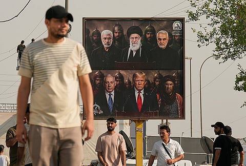A man walks past a billboard depicting slain Iraqi militia commander Abu Mahdi al-Muhandis, top left, slain former Iranian Supreme Leader Ayatollah Ali Khamenei, top center, and slain Iranian commander Qassem Soleimani, top right, above images of Israeli Prime Minister Benjamin Netanyahu, bottom left, and U.S. President Donald Trump, bottom center, during celebrations marking the complete withdrawal of U.S. troops from Iraq, in Baghdad, Iraq, Wednesday, Sept. 30, 2026. 
