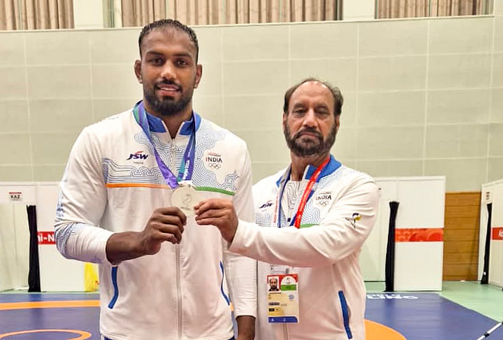 India's Greco-Roman wrestler Nitesh Siwach, left, poses with his silver medal along with national coach Hargobind Singh after winning the medal at the Aichi-Nagoya Asian Games, in Nagoya, Japan. Siwach secures the first silver medal in Greco-Roman wrestling at the Asian Games since 1962.  - | Photo: PTI